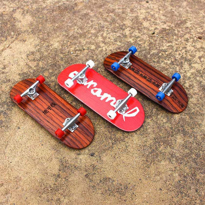 Three wooden fingerboards with red, white, and blue wheels on a concrete surface.