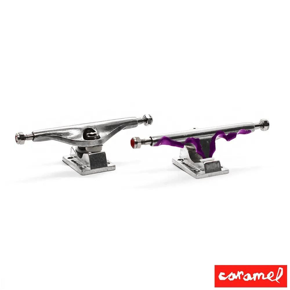 Two silver fingerboard trucks, one plain and one with purple Halloween-themed accents.